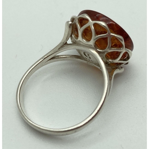 187 - A modern design silver and amber dress ring by The Genuine Gem Company. A cabochon of amber in a pie... 