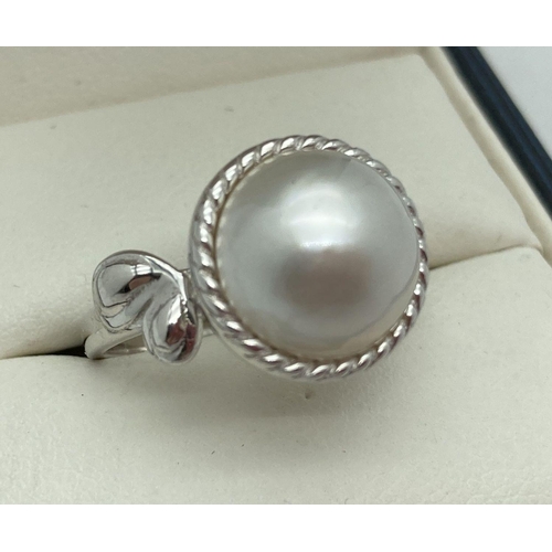 189 - A modern design silver dress ring set with a single white Mabe pearl. Simple floral design to one si... 