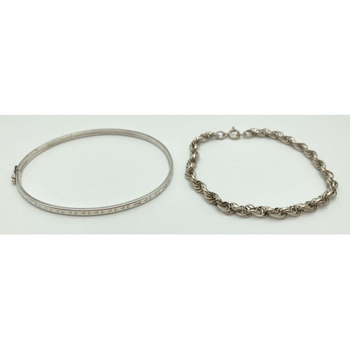 204 - 2 silver bracelets. A rope style bracelet with spring clasp and a thin hinged bangle with floral eng... 