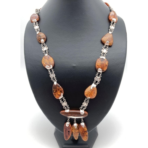 212 - A modern design amber and silver necklace with fixed drop style pendant. Alternating small silver pl... 