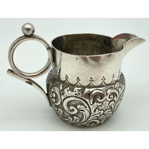 339 - A small Victorian silver cream jug decorated with scrolls and waves of foliage. Loop design handle s... 