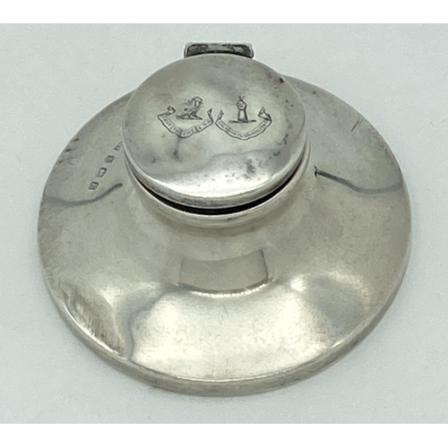 365 - A silver hinge lidded capstan inkwell with clear glass liner and bakelite base. Lid is engraved with... 