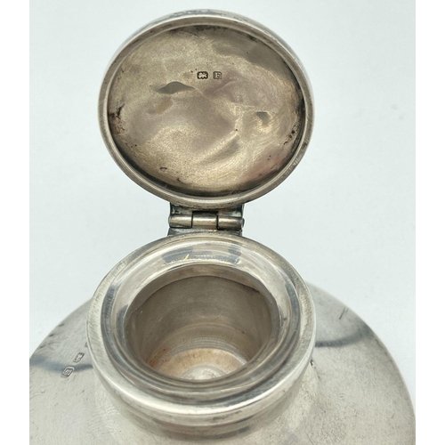 365 - A silver hinge lidded capstan inkwell with clear glass liner and bakelite base. Lid is engraved with... 