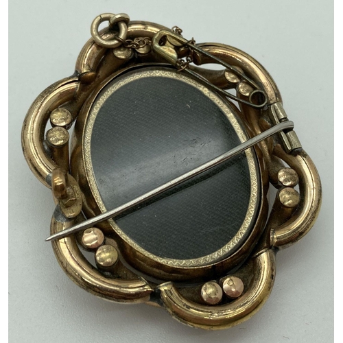 1011 - A large Victorian mourning brooch with rotating central panel and pinchbeck mount. Swivel panel feat... 