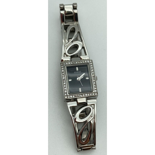 1047 - A ladies stainless steel bracelet wristwatch by Guess. Square case set with small crystals. Black fa... 