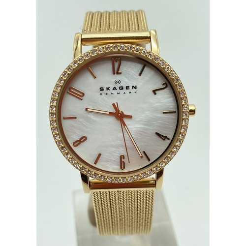 1051 - A ladies Skagen, Denmark slimline wristwatch with mother of pearl face and gold tone mesh strap. Gol... 