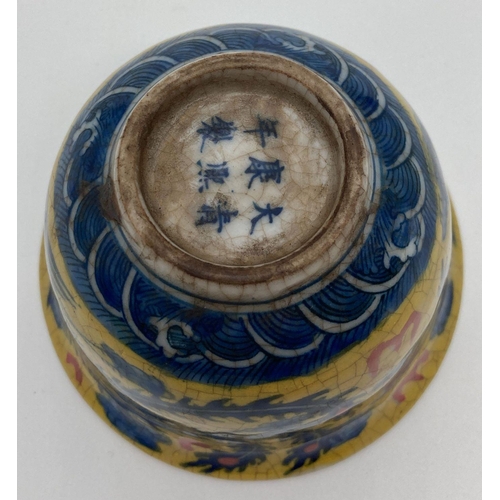 1204 - A Chinese crackle glaze ceramic tea bowl. Yellow ground with blue dragon & phoenix design to outer b... 