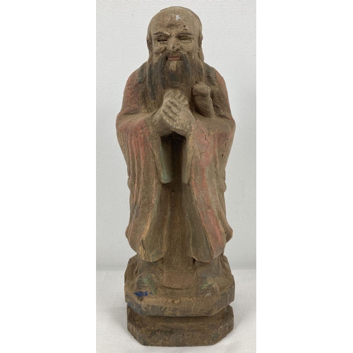 1207 - An Oriental carved wooden figure with painted detail. Approx. 26cm tall.