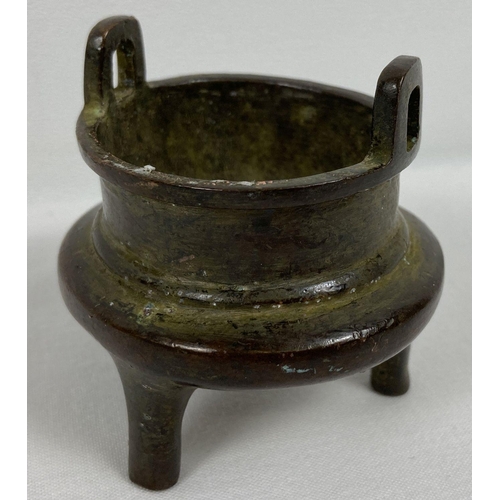 1208 - A miniature Chinese bronze censer with loop handles and raised on tapered tripod legs. Impressed mar... 