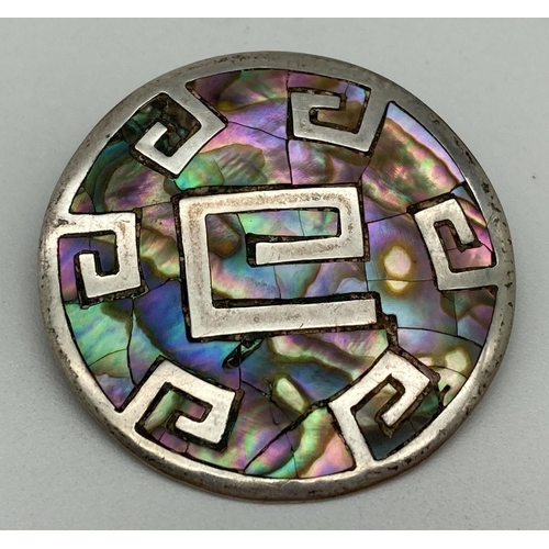 1014 - A 925 Mexican silver circular brooch/pendant with Aztec style design, set with Paua shell. Brooch pi... 