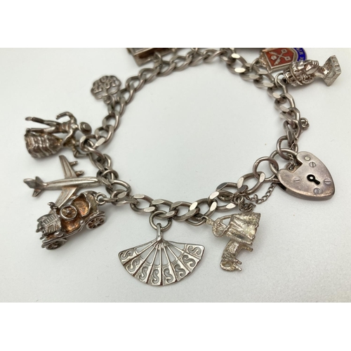 1029 - A vintage silver curb chain charm bracket with padlock clasp, safety chain and 11 silver charms. Cha... 