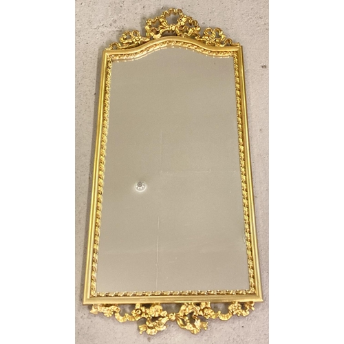 1396 - A modern gilt framed hall mirror with floral and bow detail top and bottom. Approx. 87.5cm x 39cm.