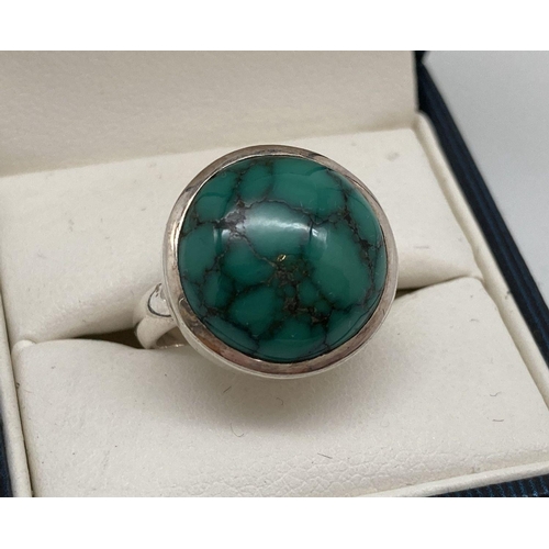 67 - A modern design silver dress ring set with a round cabochon of green turquoise. Inside of band marke... 