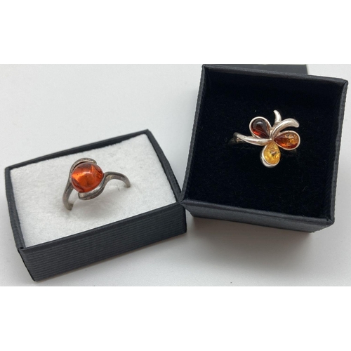 72 - 2 silver and amber set dress rings. A modern twist design mount set with a round cabochon of cognac ... 