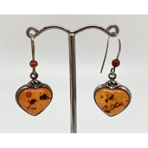 75 - A pair of white metal and cognac amber drop style heart shaped pendants and amber bead detail to hoo... 