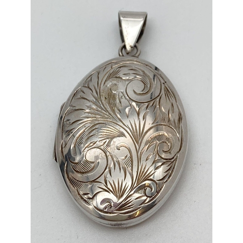 93 - A large vintage silver oval shaped locket with front engraved detail. Fully hallmarked to reverse of... 