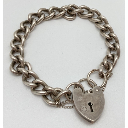 114 - A vintage silver curb chain charm bracelet with large padlock clasp and safety chain. Approx. 7 inch... 