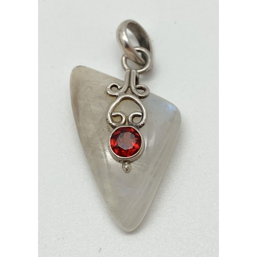 128 - A modern design moonstone and garnet pendant with silver overlay design and bale. Total length inclu... 