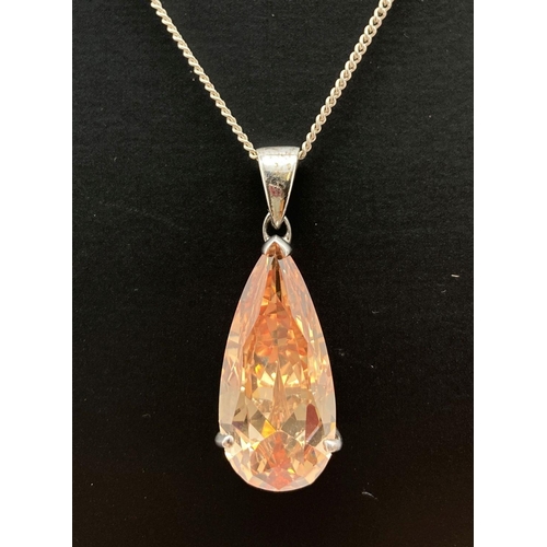 131 - A teardrop shaped pale orange crystal set in a pierced work mount on a 20 inch silver fine curb chai... 