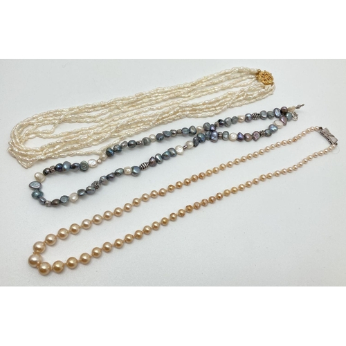 144 - 3 freshwater pearl and faux pearl necklaces. A multi strand baroque pearl necklace with decorative g... 