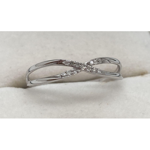 167 - A 10k white gold cross over style ring, set with 13 small diamonds. Stamped 10K inside band and mark... 