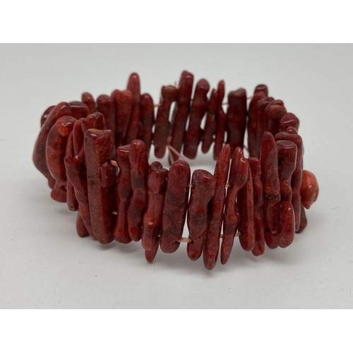 342 - A costume jewellery elasticated bracelet made from long pieces of stem coral in a deep red/brown col... 