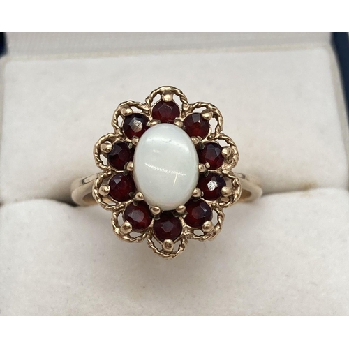 172 - A 9ct gold dress ring set with central oval opal and surrounded by a ring of garnets. Framed with a ... 