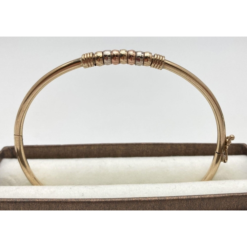 13 - A 9ct yellow gold hinged bangle with tri-coloured gold beaded detail. With fold over clasp, marked 3... 