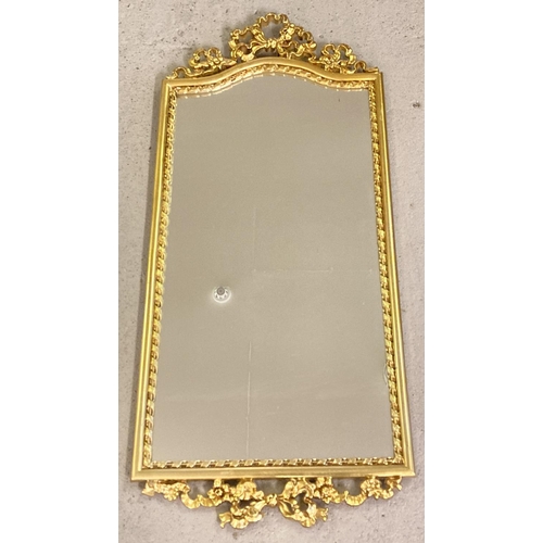 1378 - A modern gilt framed hall mirror with floral and bow detail top and bottom. Approx. 87.5cm x 39cm.