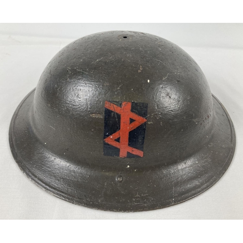 1121 - A WWII British Mk II steel helmet with chinstrap - liner missing. Field applied khaki paint finish w... 