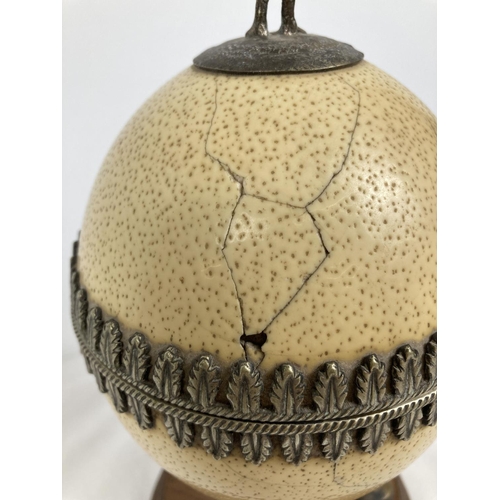 1296 - An antique lidded trinket pot made from an ostrich egg. With silver plated interior, decorative trim... 