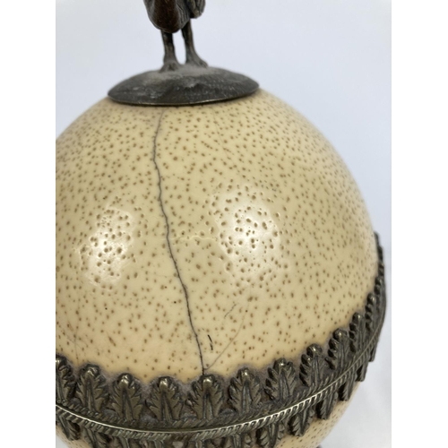 1296 - An antique lidded trinket pot made from an ostrich egg. With silver plated interior, decorative trim... 