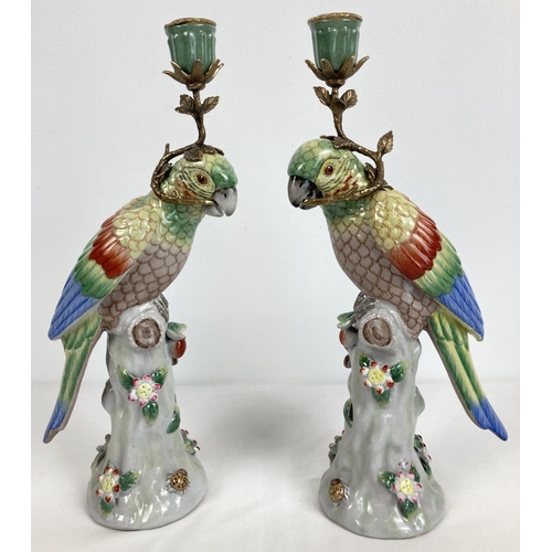 1159 - A pair of ceramic candlesticks modelled as parrots sitting atop a stump. With flower and insect appl... 