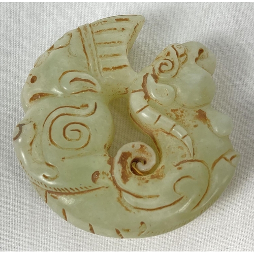 1192 - A carved jade roundel with mythical creature detail. Carved detail to both sides. Approx. 5.5cm diam... 