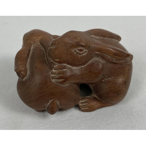 1198 - A small carved wooden figure modelled as 2 rabbits. Approx. 3.5cm tall x 5.5cm long.