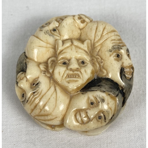 1199 - A bone netsuke carved in the form of 9 different faces. With slits to side panels and central hole c... 