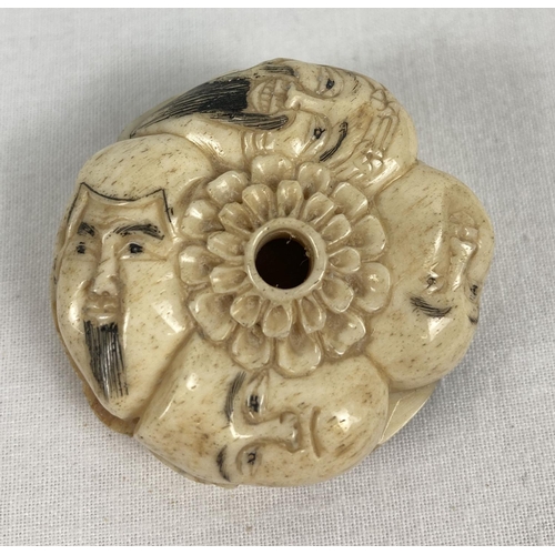 1199 - A bone netsuke carved in the form of 9 different faces. With slits to side panels and central hole c... 