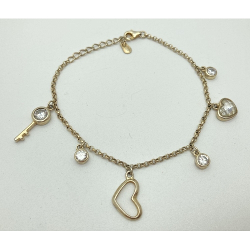 1136 - A silver gilt belcher chain bracelet with key, heart and circular drop charms. Some set with clear s... 