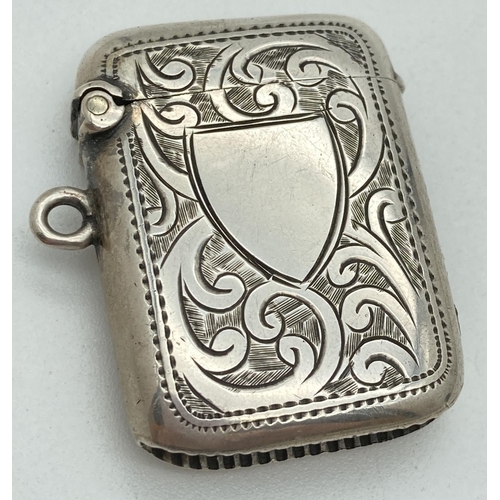 1193 - An Edwardian silver vesta case with engraved foliate & scroll detail front & back. Central empty shi... 