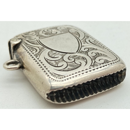 1193 - An Edwardian silver vesta case with engraved foliate & scroll detail front & back. Central empty shi... 