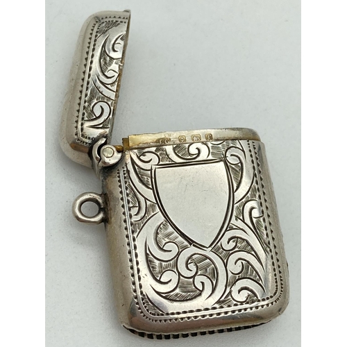 1193 - An Edwardian silver vesta case with engraved foliate & scroll detail front & back. Central empty shi... 