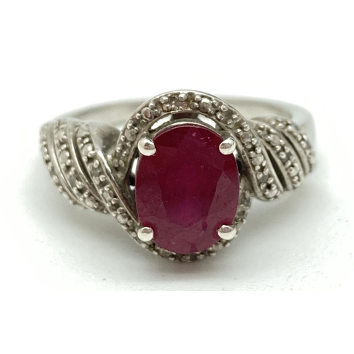 1087 - A silver ruby and diamond cocktail ring. Central oval cut  ruby in decorative pierced illusion mount... 