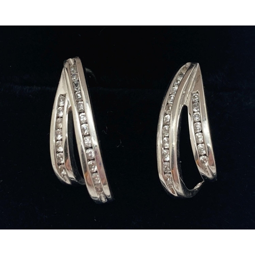 1090 - A pair of 9ct white gold split design earrings with channel set diamonds. Each set with 19 small rou... 