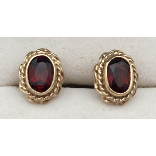 1105 - A pair of 9ct gold, twist mount set, garnet stud earrings. Fully hallmarked to posts, complete with ... 