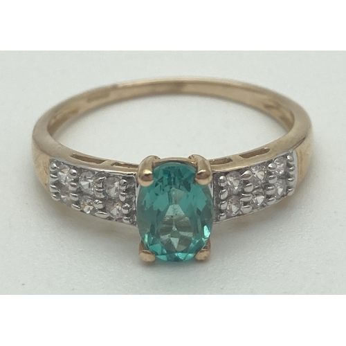 1121 - A 9ct yellow gold dress ring set with green Apatite flanked by rows of zircons. Central oval cut sto... 