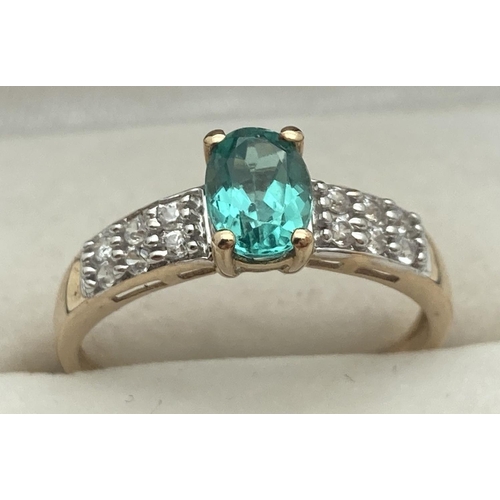 1121 - A 9ct yellow gold dress ring set with green Apatite flanked by rows of zircons. Central oval cut sto... 