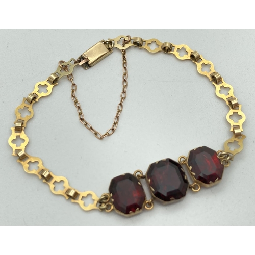 1123 - A 9ct gold linked 3 stone bracelet set with garnets. With push box clasp and safety chain. Tests as ... 