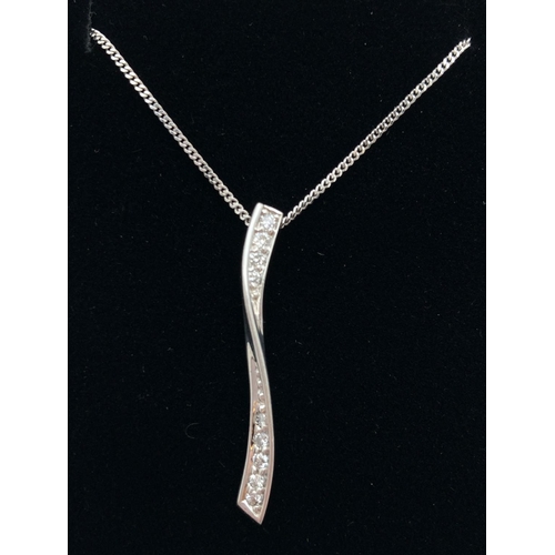 1005 - A modern 9ct white gold twist design pendant set with diamonds. On an 18