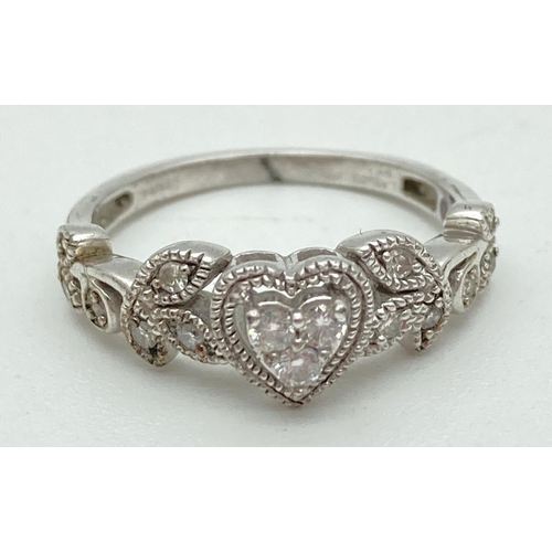 1152 - A silver and diamond dress ring set with 15 small diamonds. 3 stones in a central heart shaped setti... 