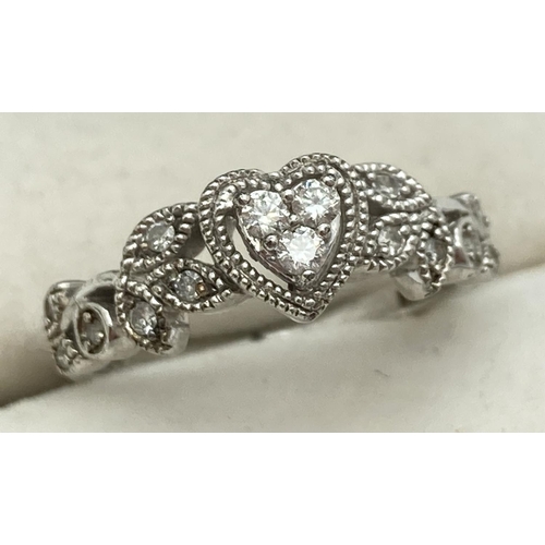 1152 - A silver and diamond dress ring set with 15 small diamonds. 3 stones in a central heart shaped setti... 